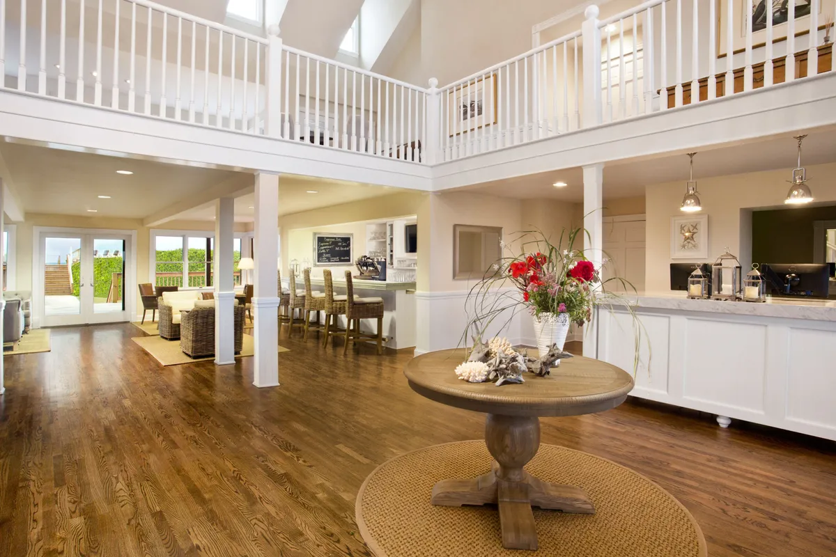 A welcoming kitchen and dining area featuring a central round table with a vibrant floral arrangement and a kitchen bar. Open sliding doors lead to an outdoor space, creating an airy, seamless connection between indoors and outdoors.
